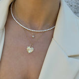 Close-up of a person layering three necklaces with north star and heart pendants on a neutral background. with a seed pearl necklace