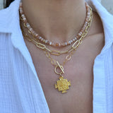 Gold necklace with a pendant worn by a person against a white background