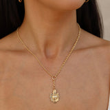 14kt gold-filled chain with a bronze sacred heart necklace  worn by a young woman  against a neutral background